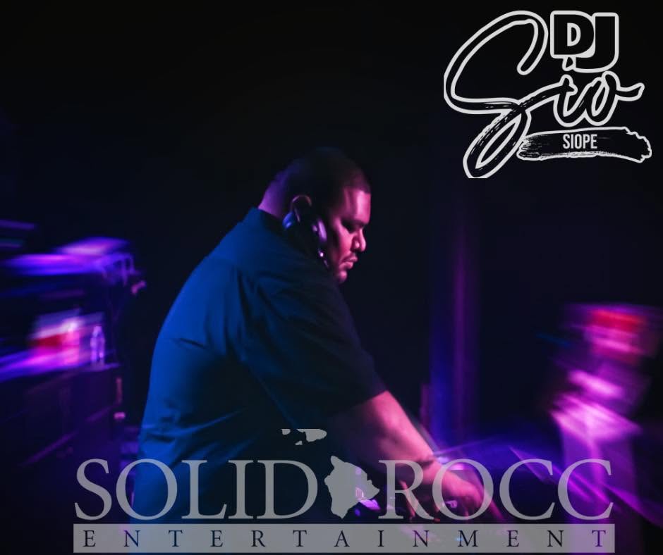 DJ Sio performing at the turntables under purple lights